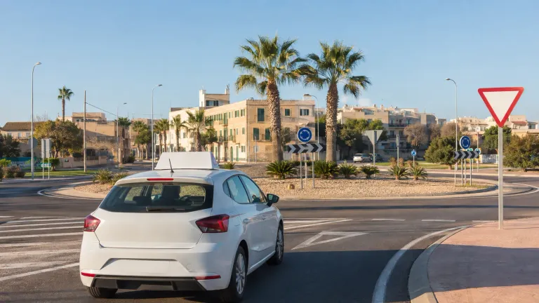 Coche de autoescuela acercándose a una glorieta en Palma de Mallorca
